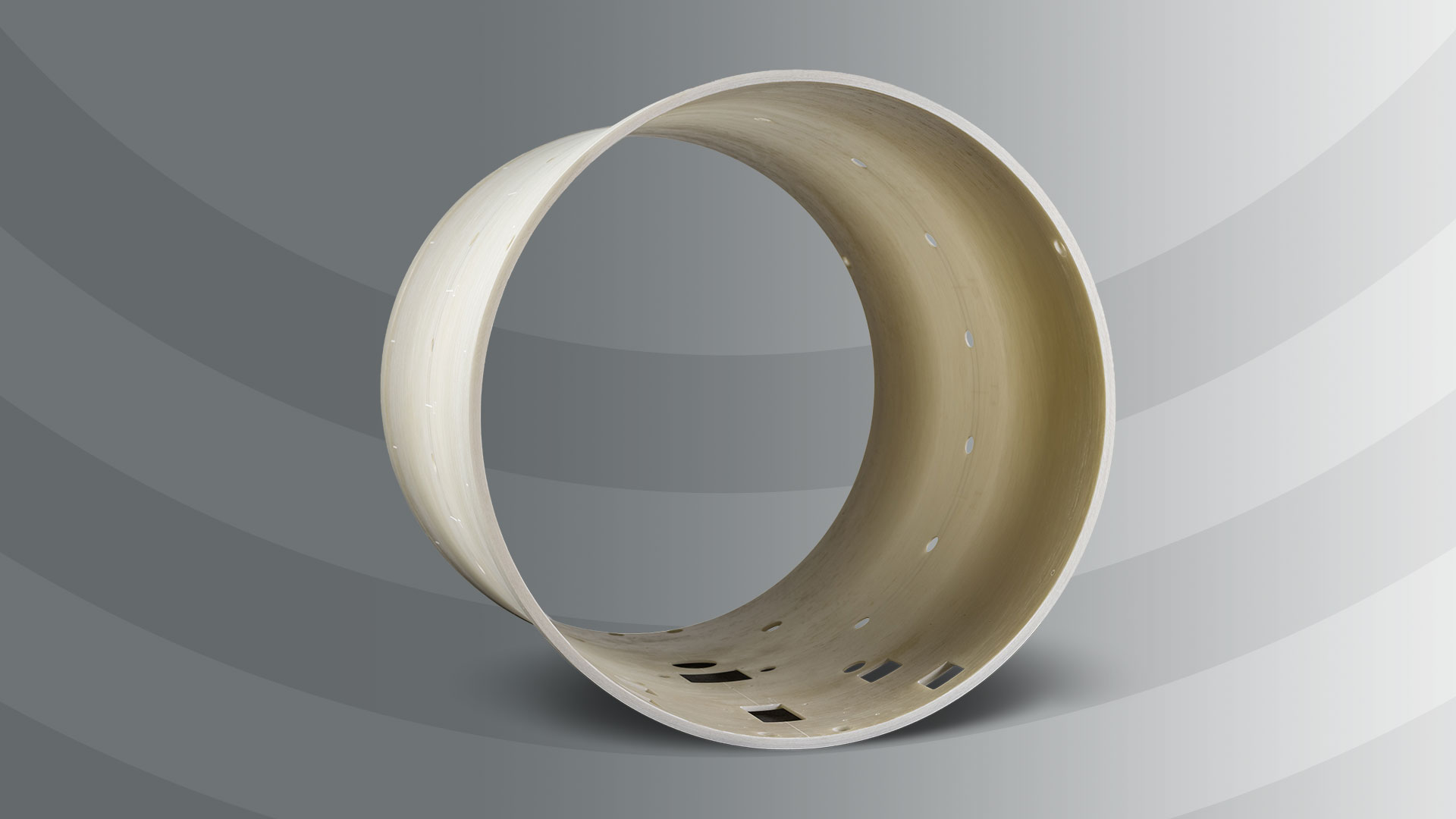 A large, light-colored cylindrical ring with rectangular cutouts stands upright against a gradient gray background with curved stripes.
