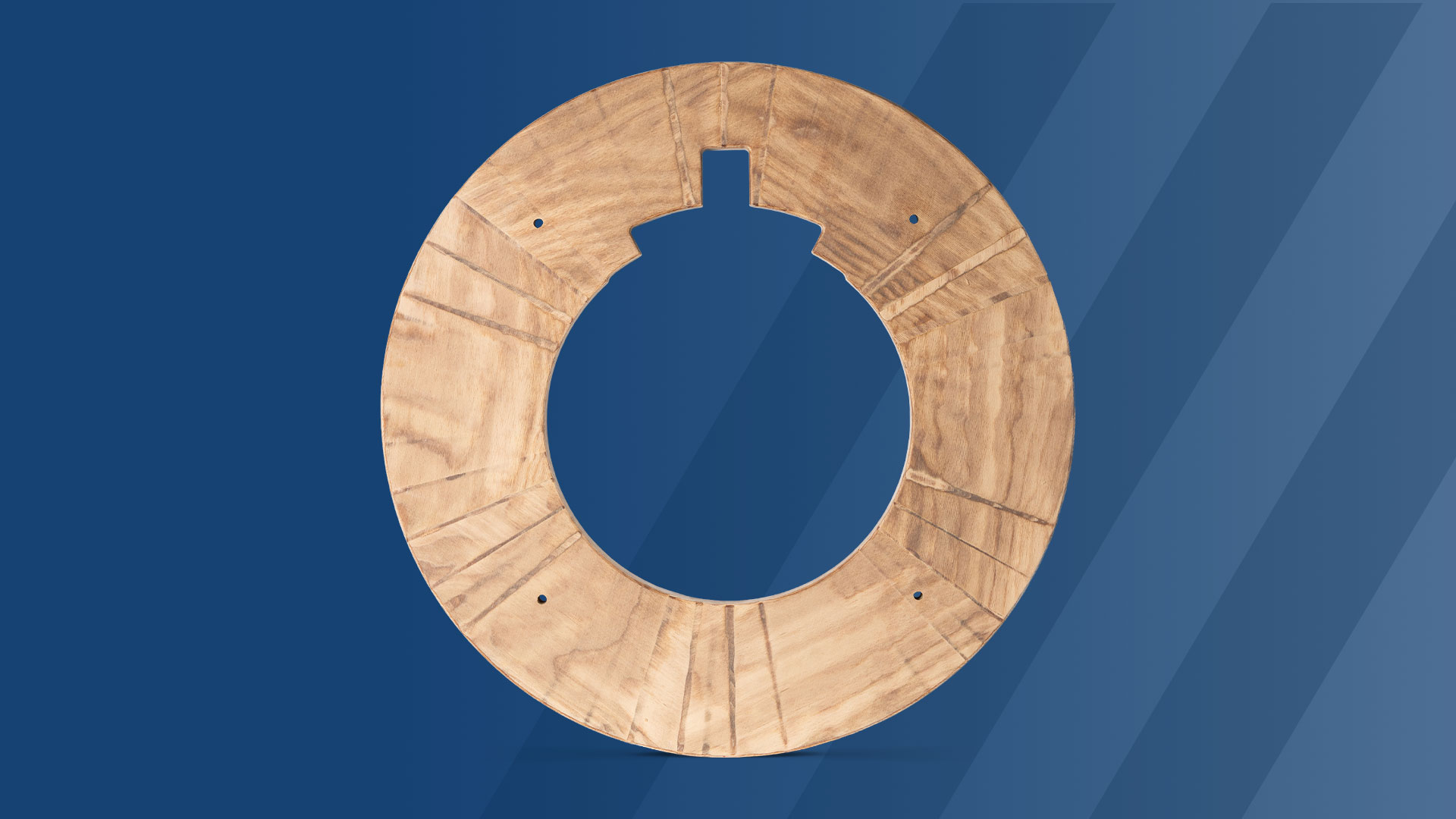 A round wooden ring with a notch and four small holes, displayed on a blue background with diagonal stripes.