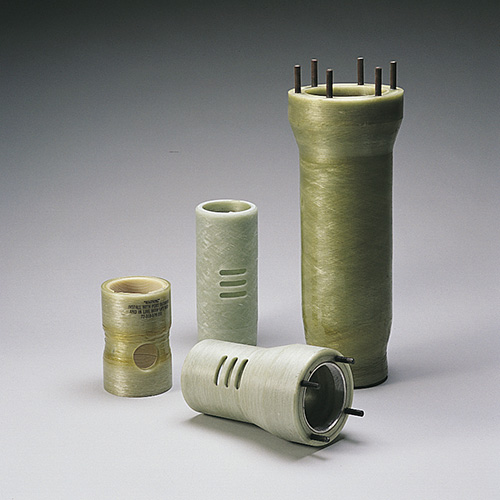 Four cylindrical fiberglass components stand upright on a gray surface, each varying in height and design, with the tallest having metal pins on top.