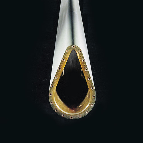 Close-up of a hollow, teardrop-shaped metal object with bolts around the edge, viewed from the end against a black background.