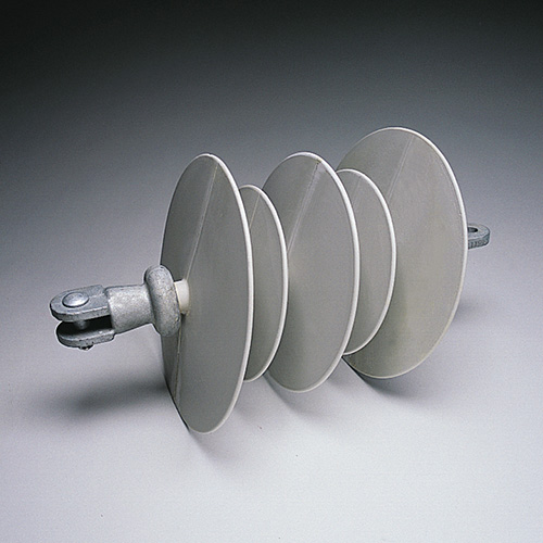 A gray electrical insulator with four round, disc-like segments and a metal attachment at one end, placed on a plain, light-colored surface.
