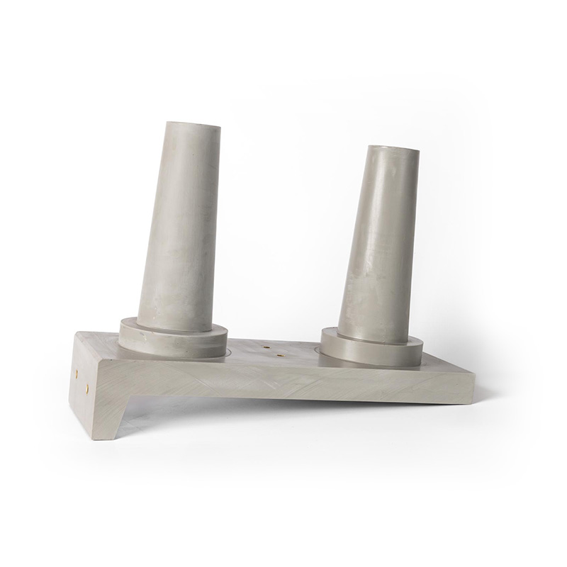 A modern, abstract concrete sculpture with two cylindrical cones set at angles on a rectangular base, against a plain white background.