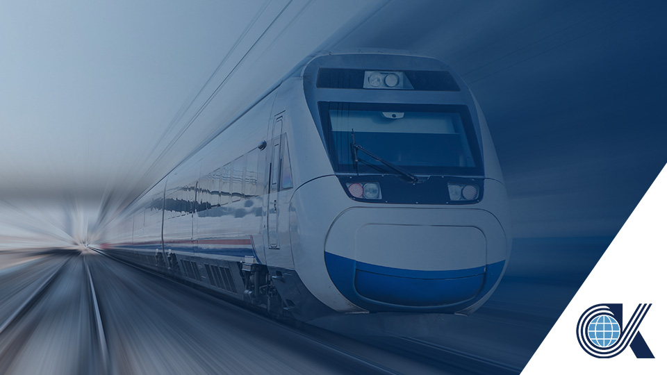A modern high-speed train travels quickly on tracks, with motion blur emphasizing its speed. A blue and white logo featuring a globe and the letter C appears in the bottom right corner.