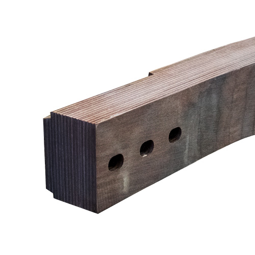 A close-up of a wooden beam with three round holes drilled through it and notches cut on the upper left edge. The wood grain is visible, and the beam appears stained or weathered.